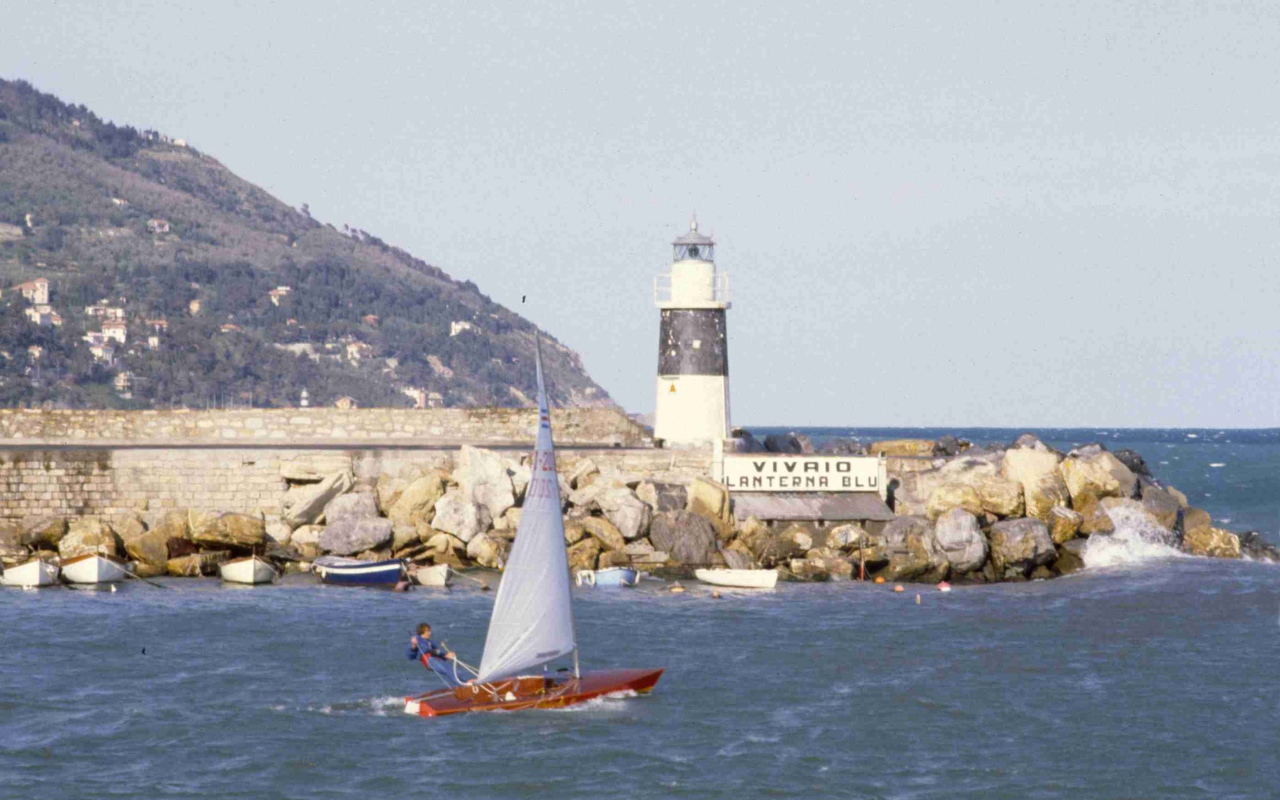 Лодка на фоне маяка на курорте Империя, Италия