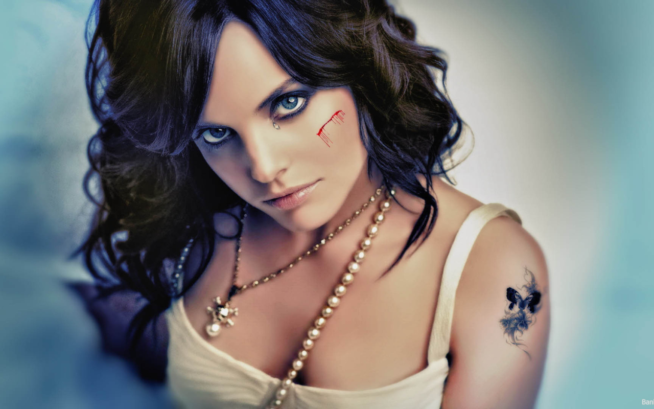 Шрам на щеке и татуировка на плече у девушки