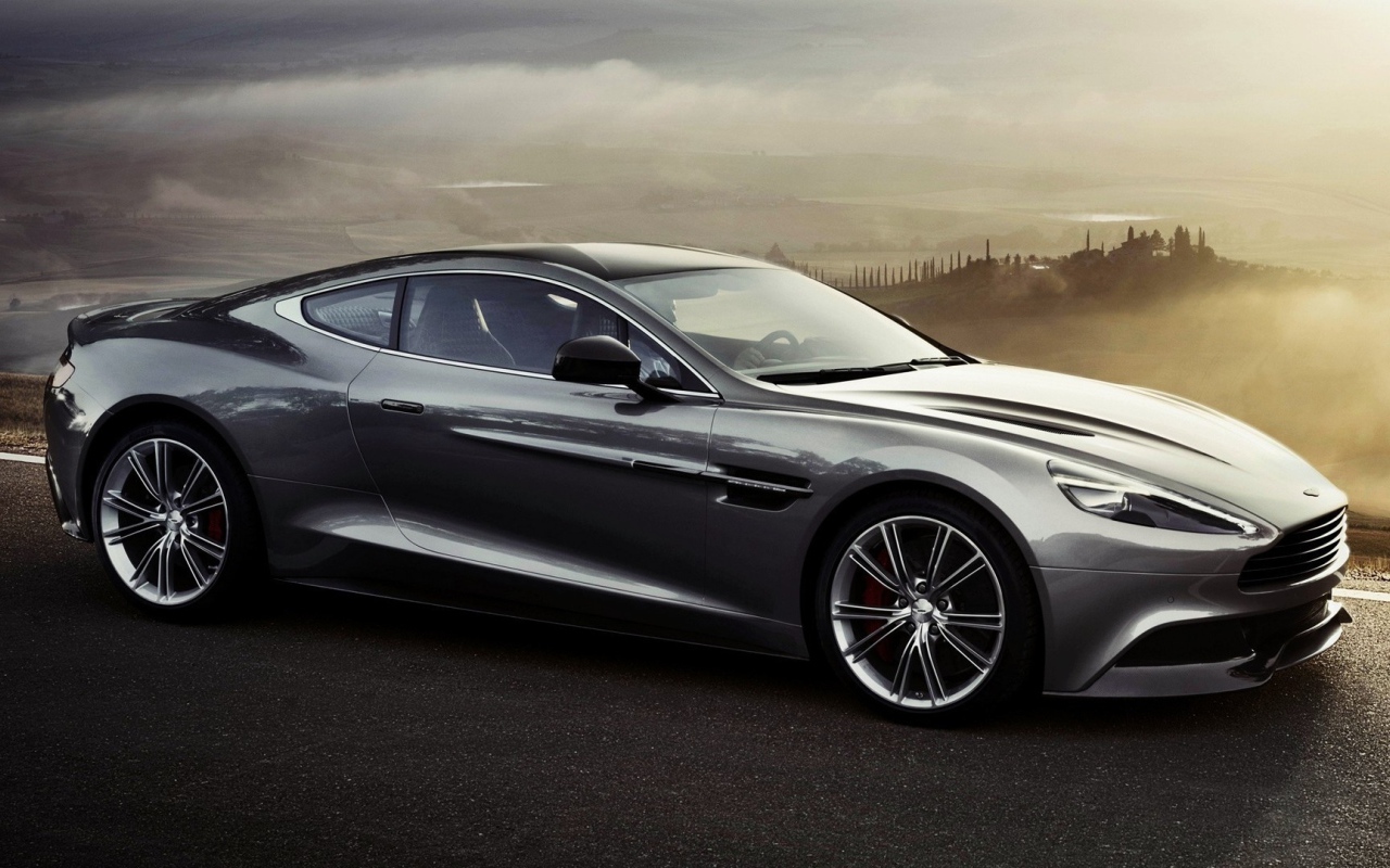 Темно серый Aston Martin на фоне туманной долины
