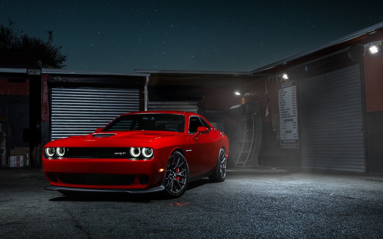 Красный Dodge Challenger Hellcat у гаража