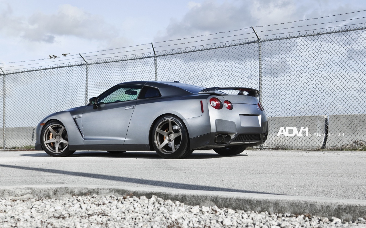 Серый Nissan Skyline GT-R R35 у забора из сетки