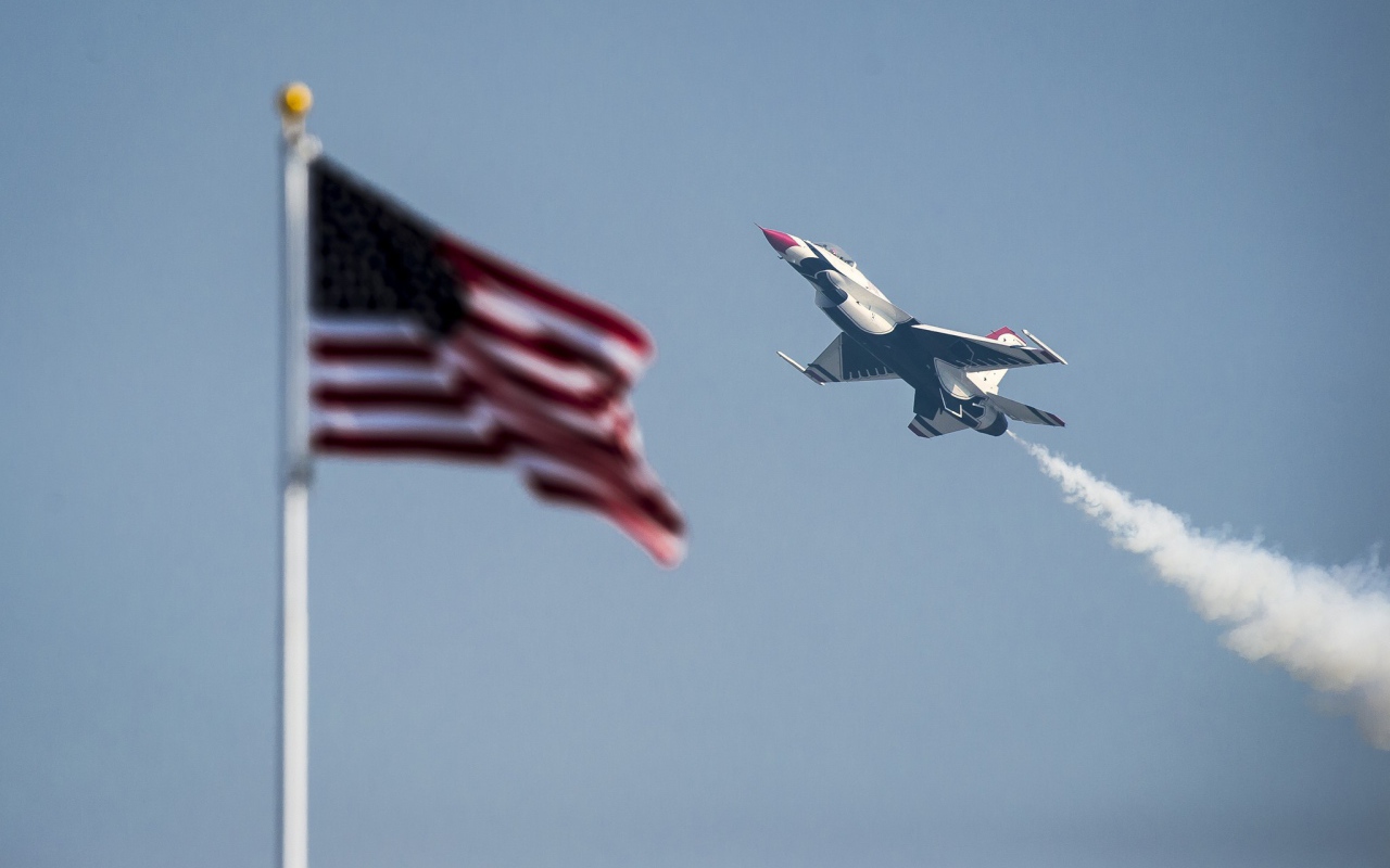 Истребитель F-16 Fighting Falcon пролетает над флагом США