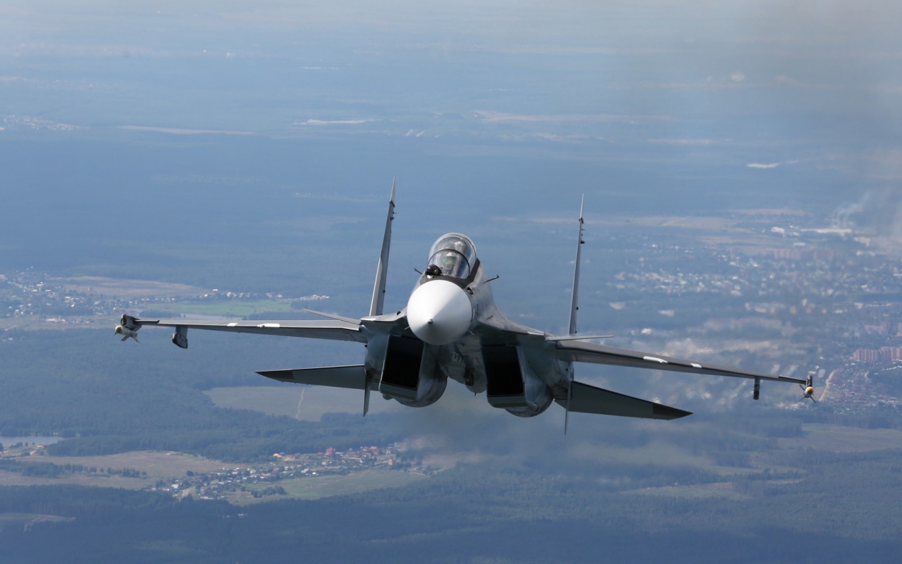 Самолет СУ-27 летит над городом