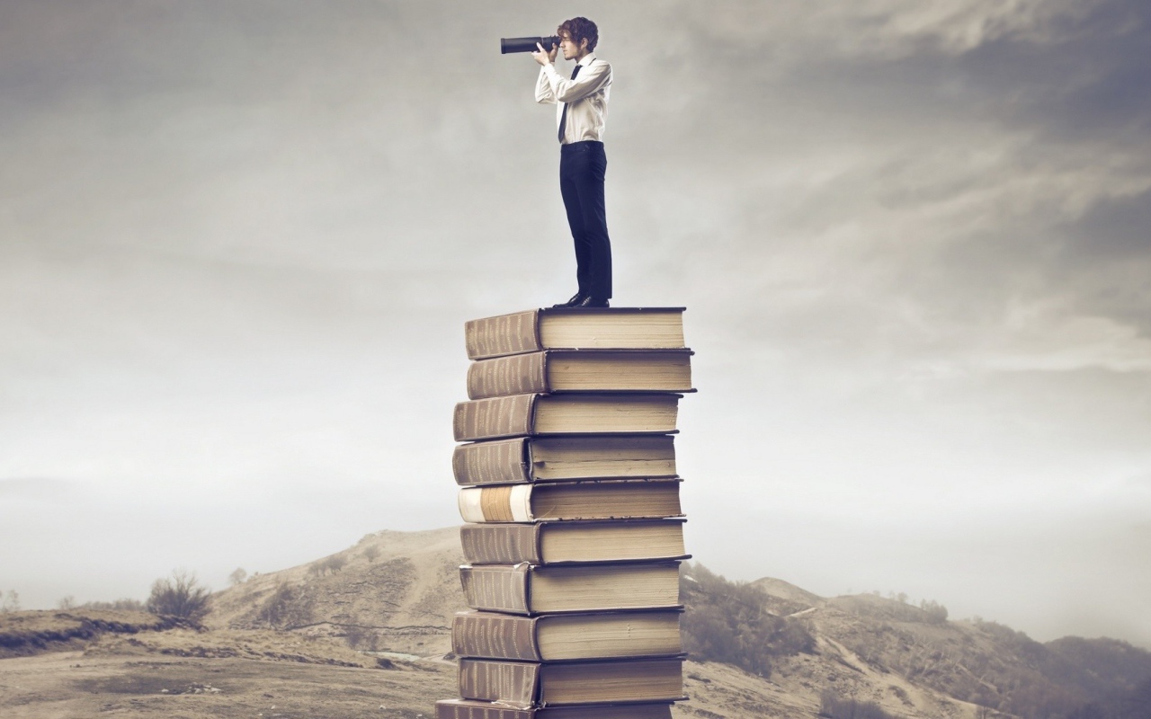 Мужчина с подзорной трубой на стопке книг