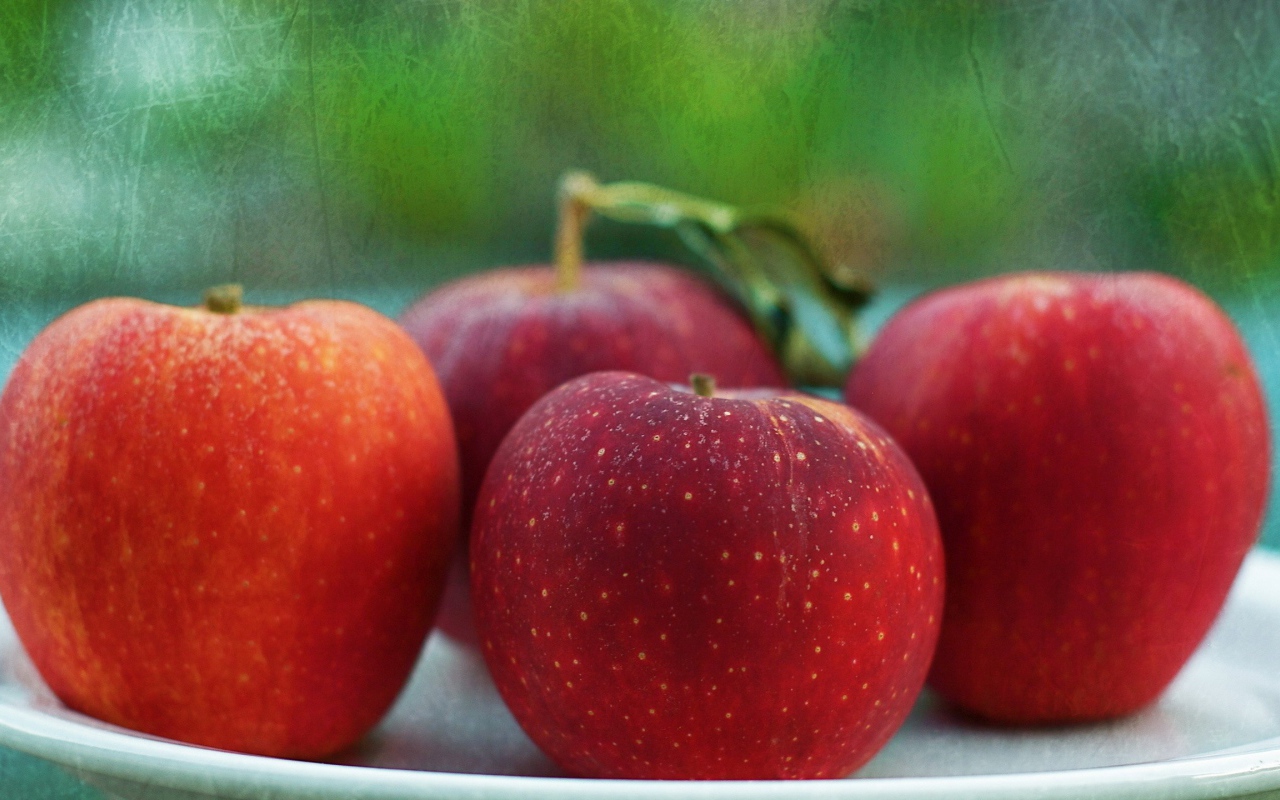 Четыре красных яблока на тарелке