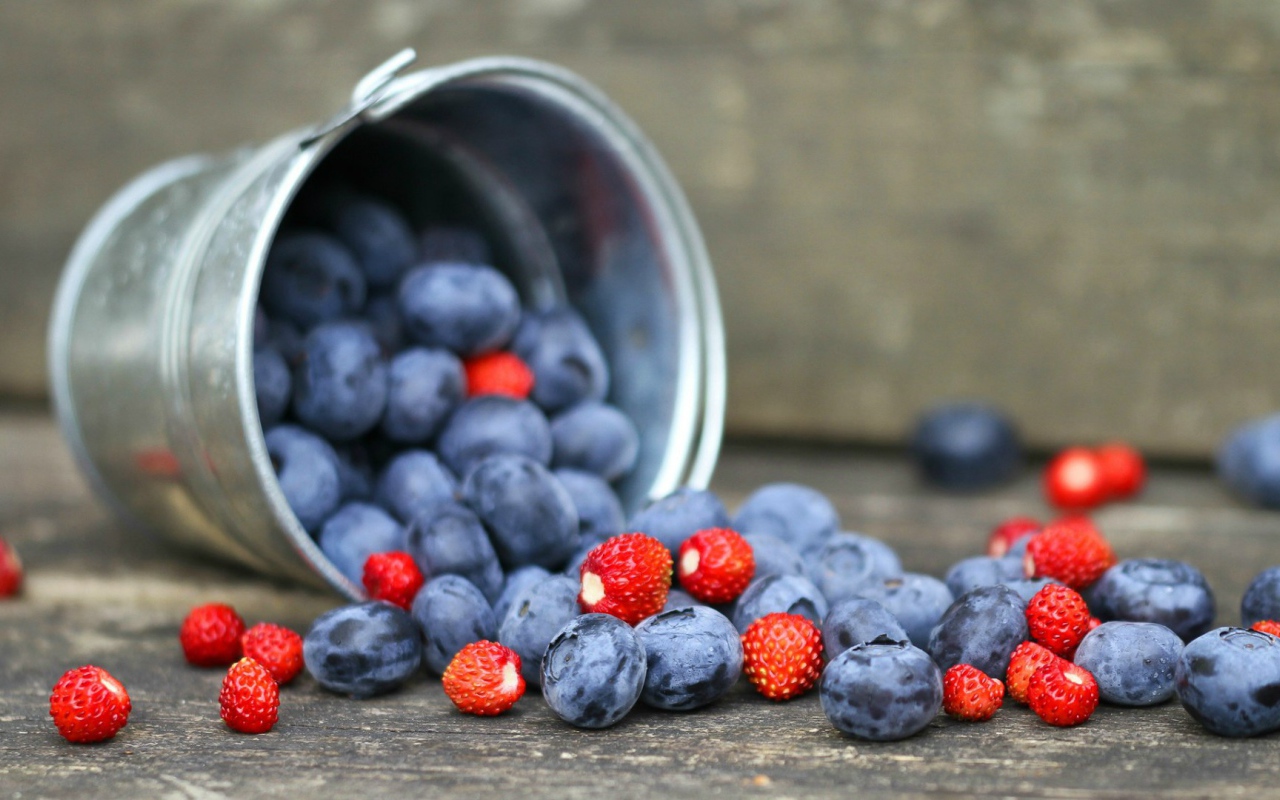 Плоды клубники и сливы в ведре