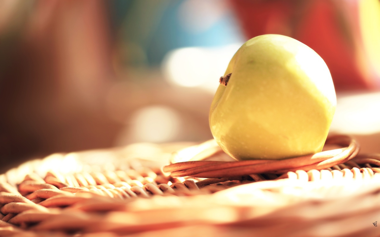 Белое яблоко на плетеной подставке