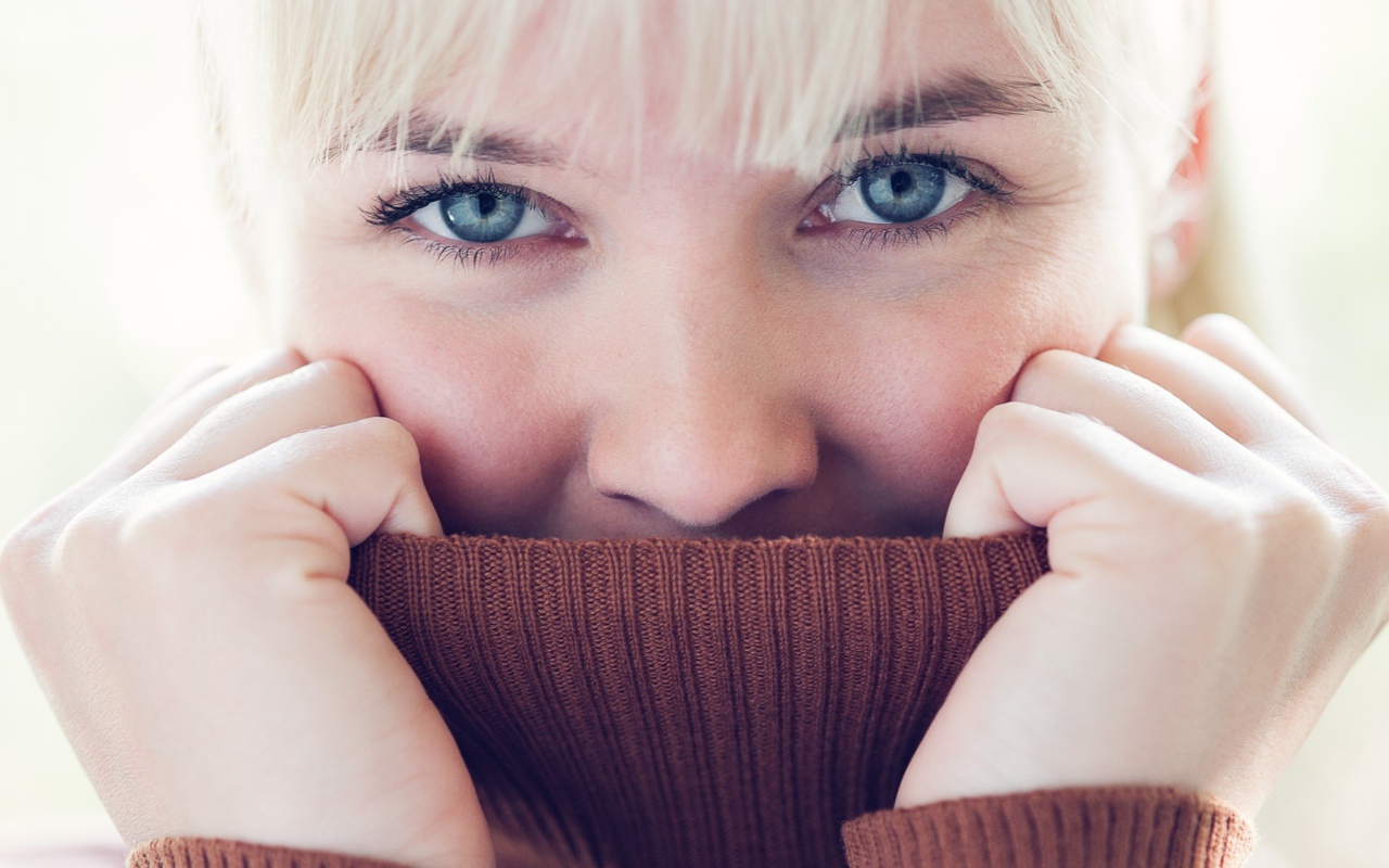 Блондинка прячет лицо в вороте свитера
