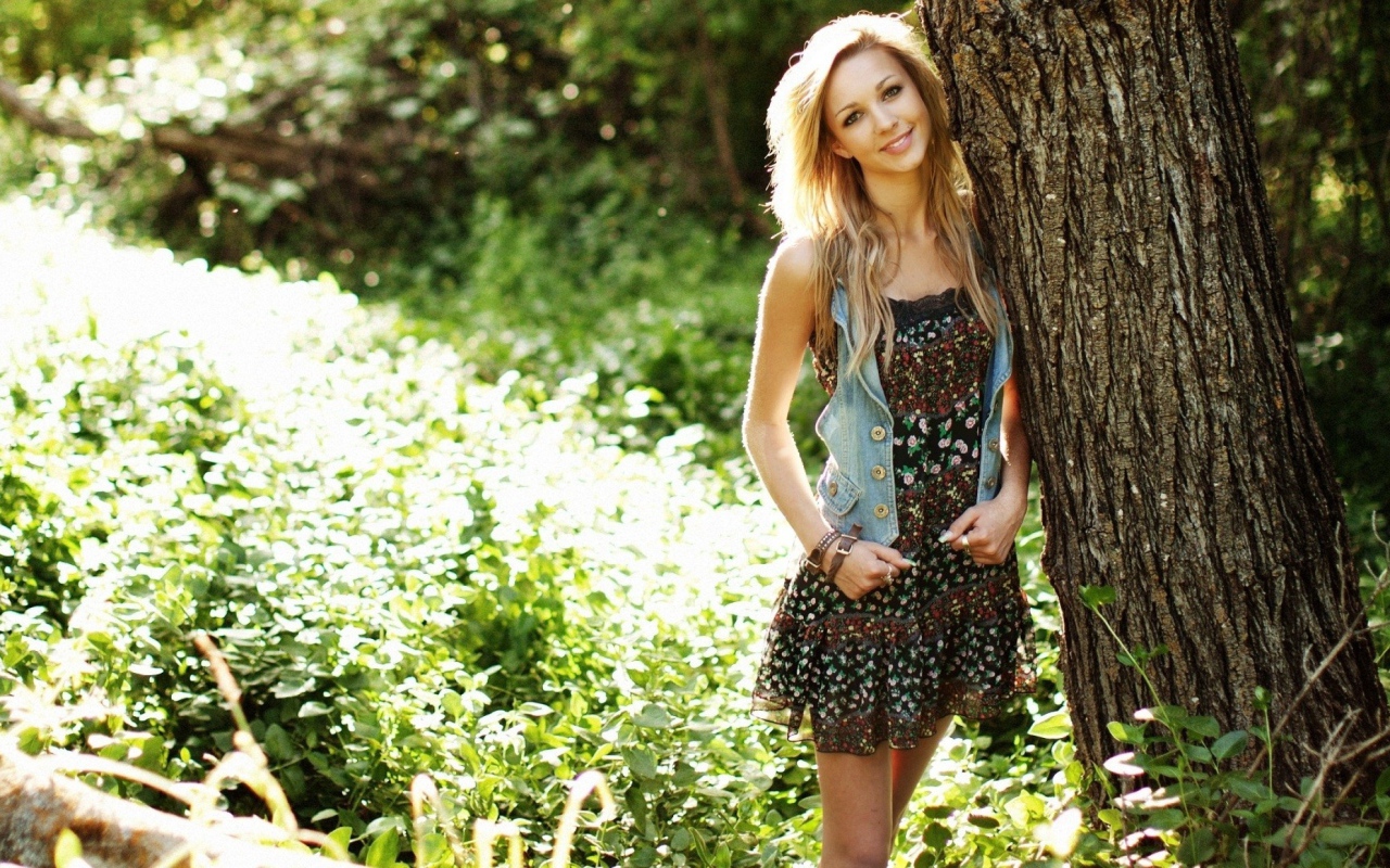 Милая блондинка прислонилась к дереву