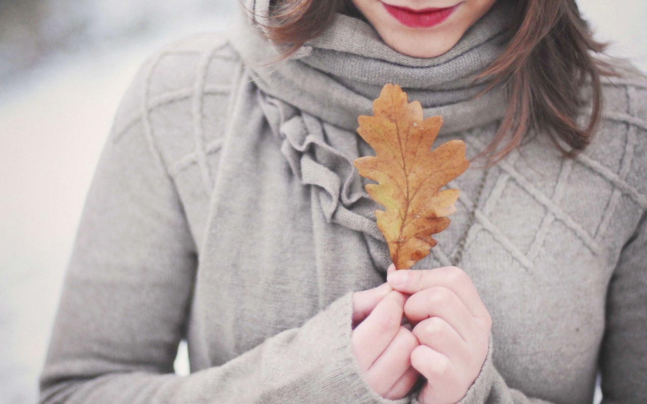 Девушка держит в руках желтый лист