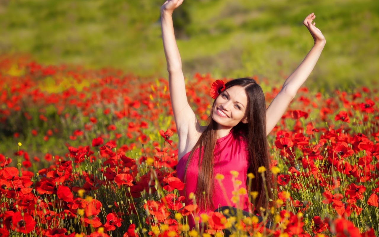 Girl in a red dress on a field of poppies