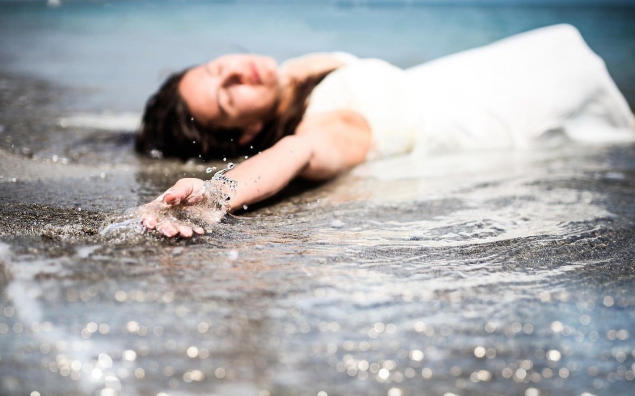 Девушка лежит в волне прибоя