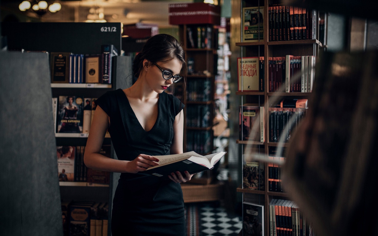 Девушка читает среди книжных полок
