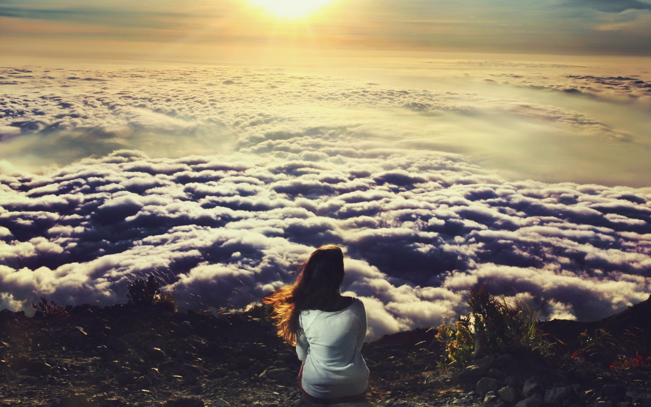Девушка сидит и смотрит на облака