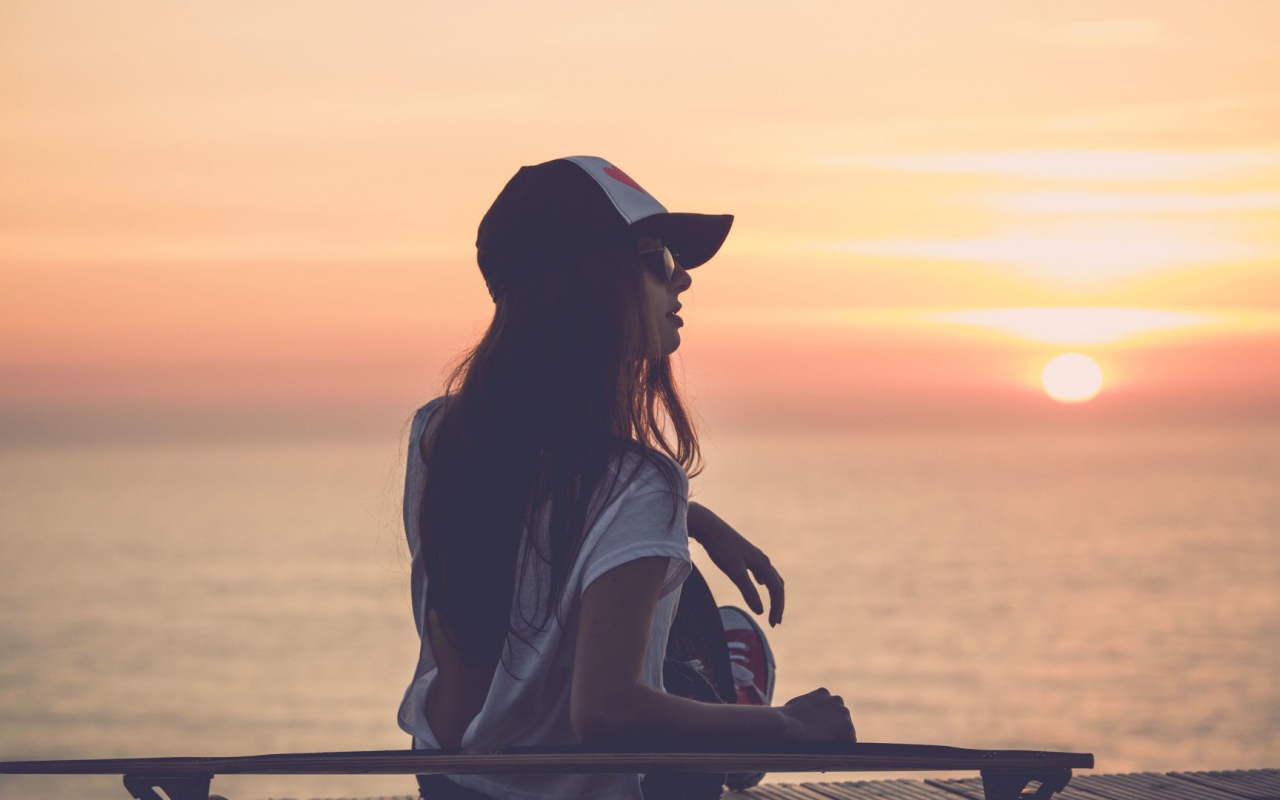 Девушка смотрит на закат на пляже