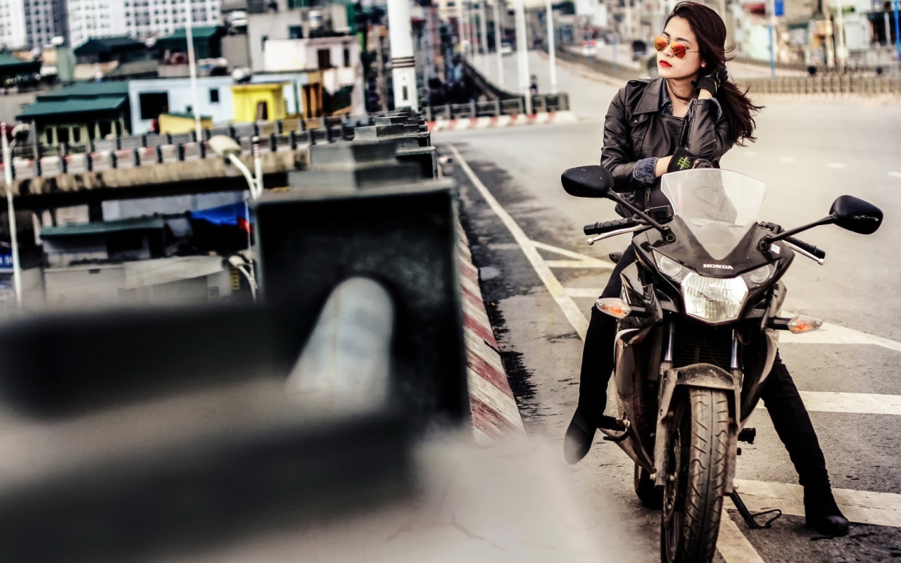 Девушка в темных очках сидит на мотоцикле