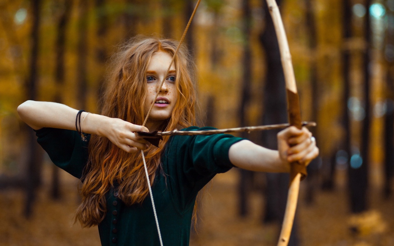 Рыжая девушка целится из лука