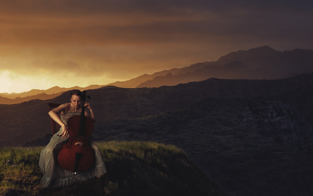 Девушка играет на виолончели на фоне гор