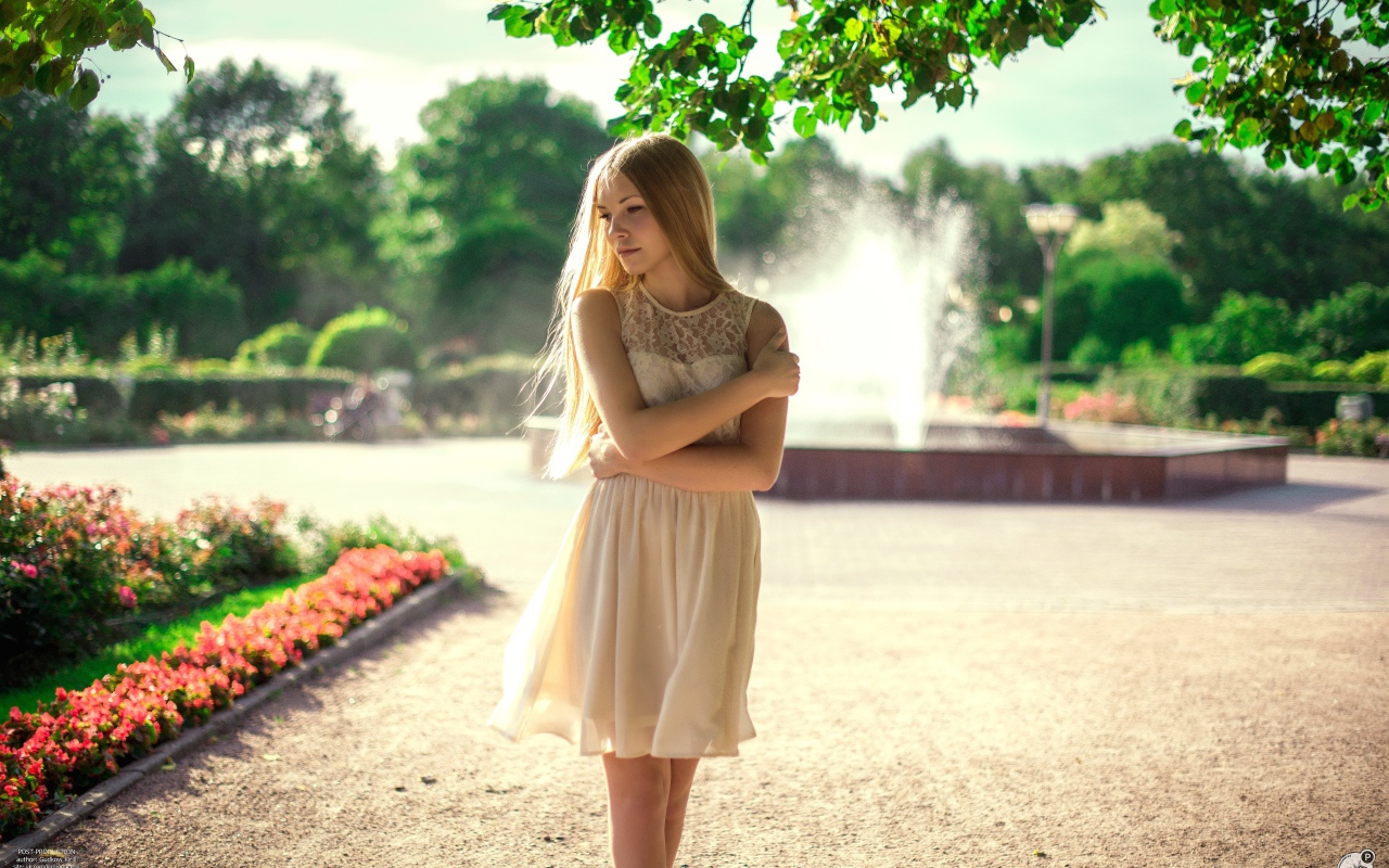 Блондинка в парке на фоне фонтана