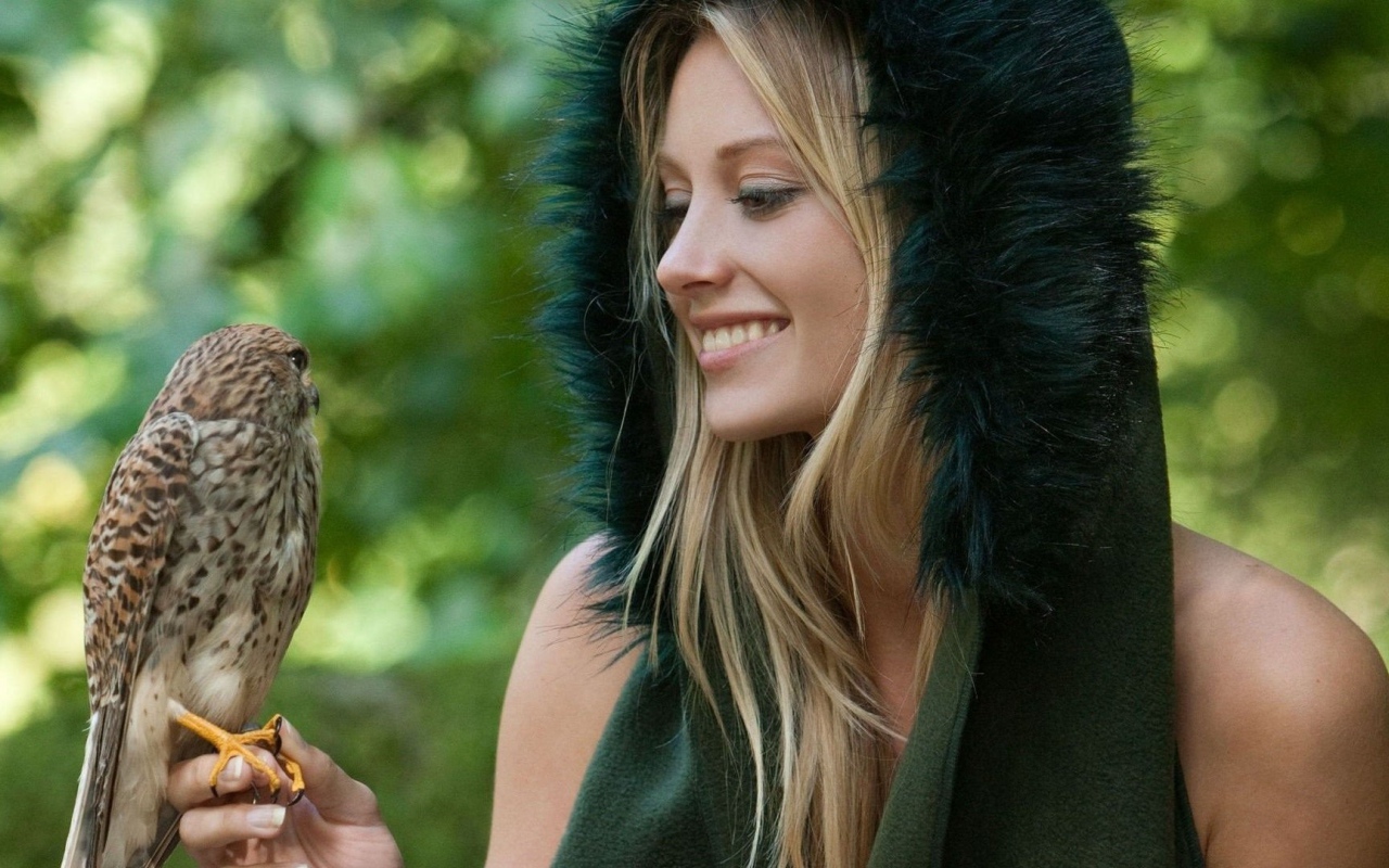 Девушка в меховой накидке держит на руке птицу