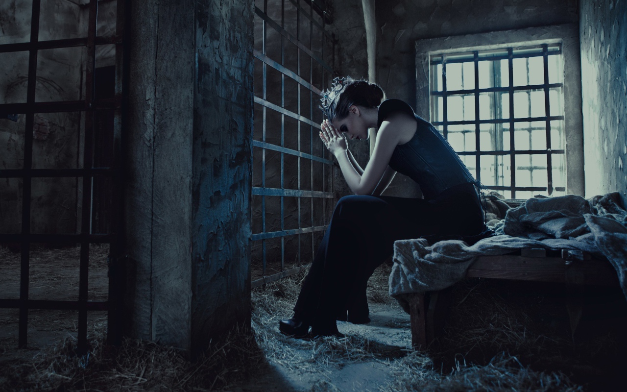 Девушка сидит за решеткой в тюрьме