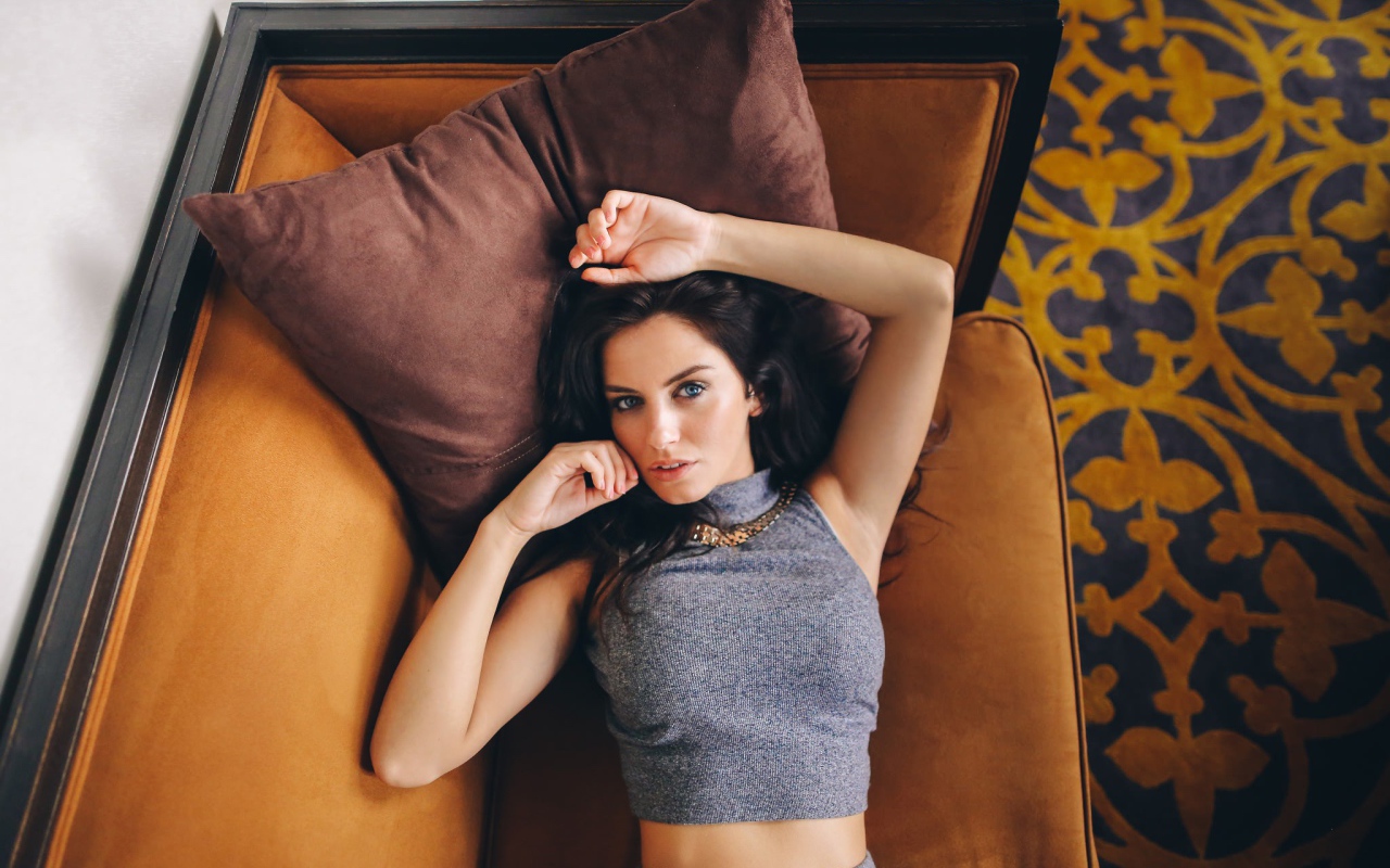 Модель Aurela Skandaj лежит на диване