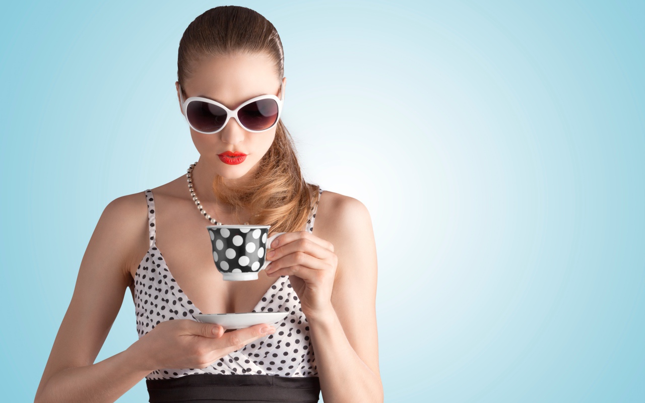 Модель в темных очках с чашкой на голубом фоне