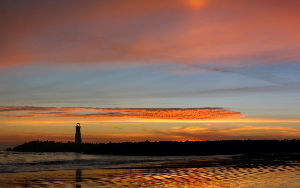 Силуэт маяка на фоне оранжевых облаков
