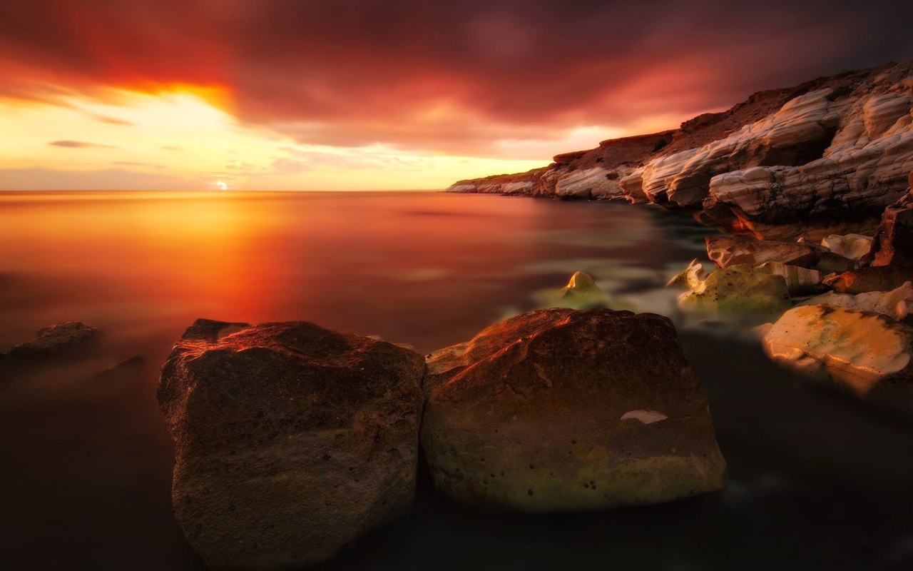 Два больших камня на берегу моря на закате