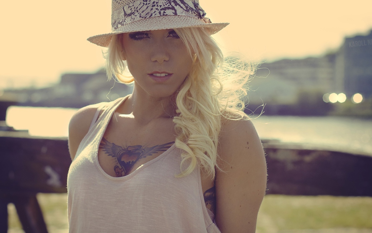 Блондинка в белой шляпе с тату на груди