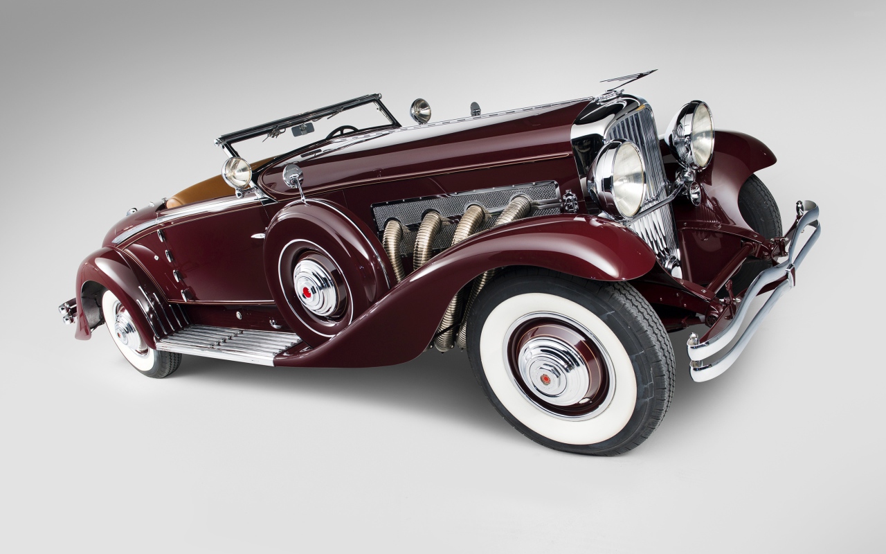 Бордовый ретро автомобиль Duesenberg Model J 530 на сером фоне