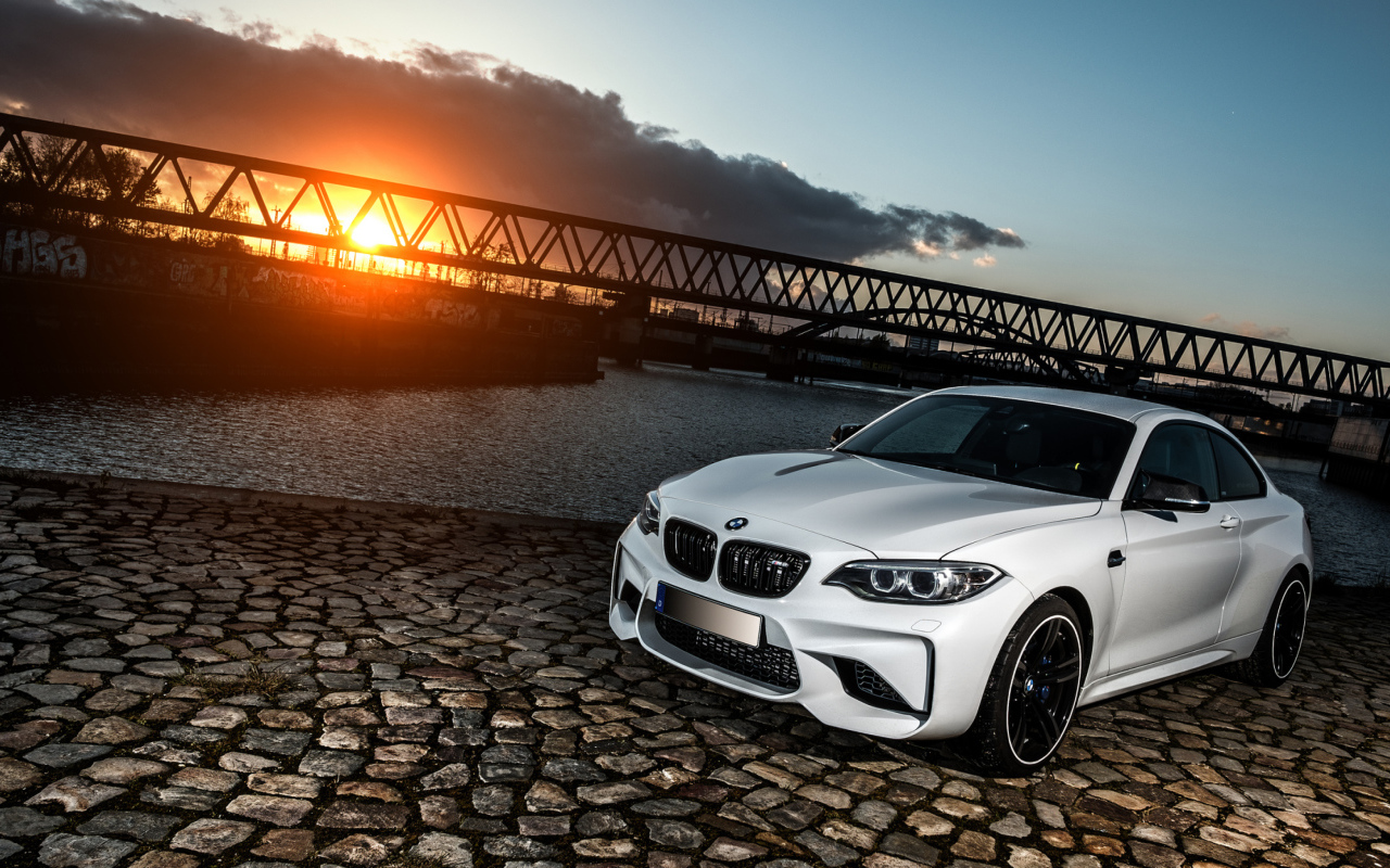 Белый автомобиль BMW M2 на фоне заката 
