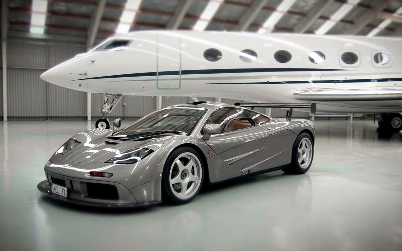 Спортивный автомобиль McLaren F1 на фоне самолета