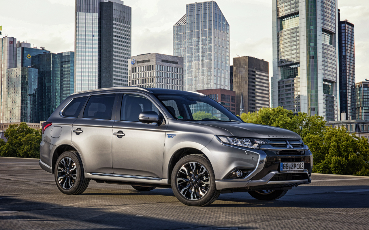 Серебристый автомобиль Mitsubishi Outlander на фоне небоскребов 