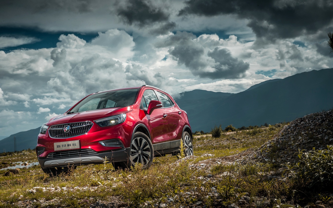 Красный автомобиль Opel Mokka на фоне облачного неба 