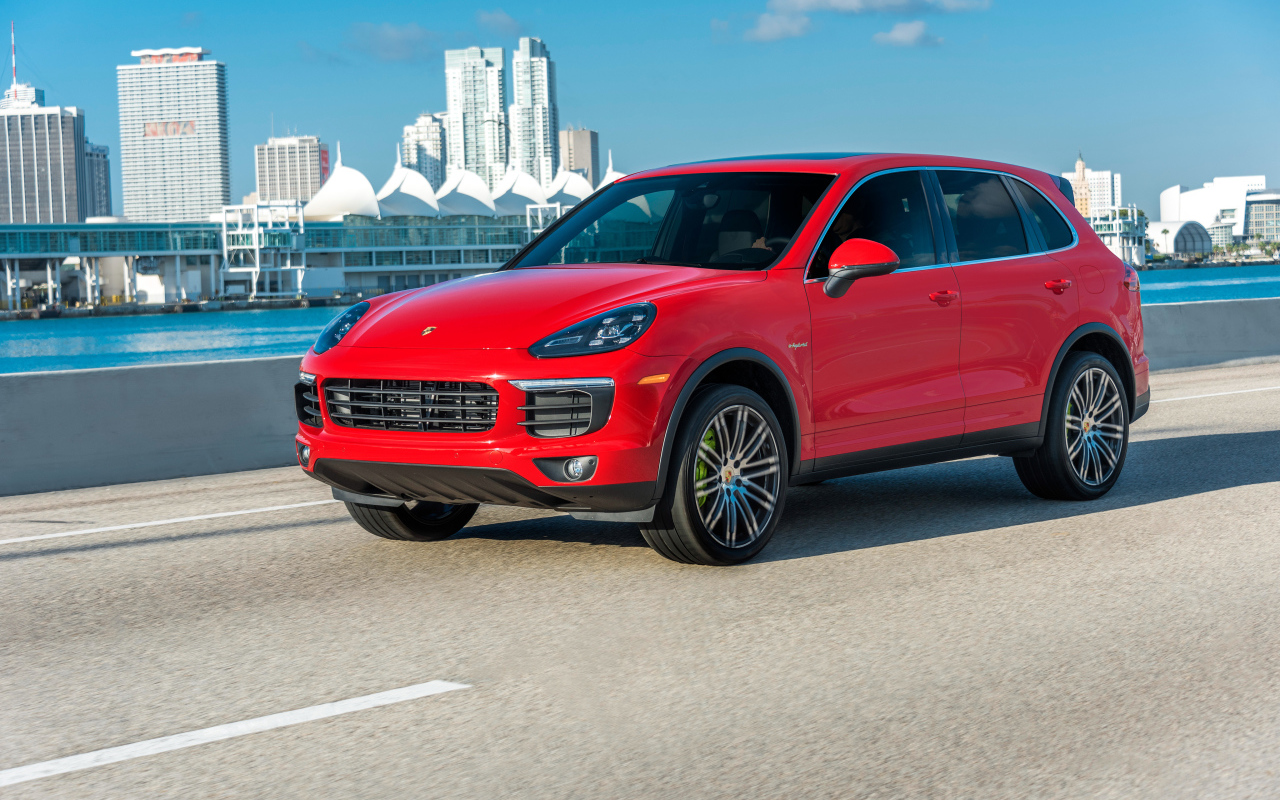 Красный автомобиль Porsche Cayenne на фоне города 