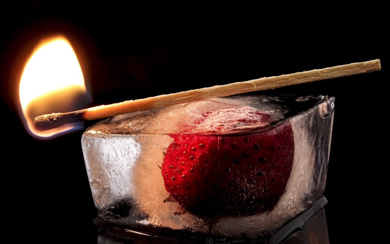 Зажженная спичка на кусочке льда с клубникой 