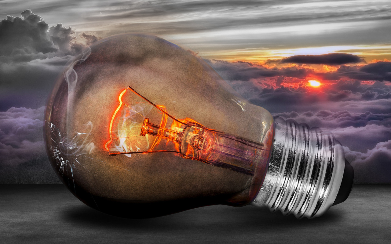 Раскаленная лампочка на фоне белых облаков в небе