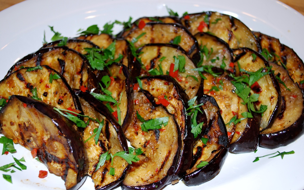 Аппетитные жареные баклажаны на тарелке с зеленью