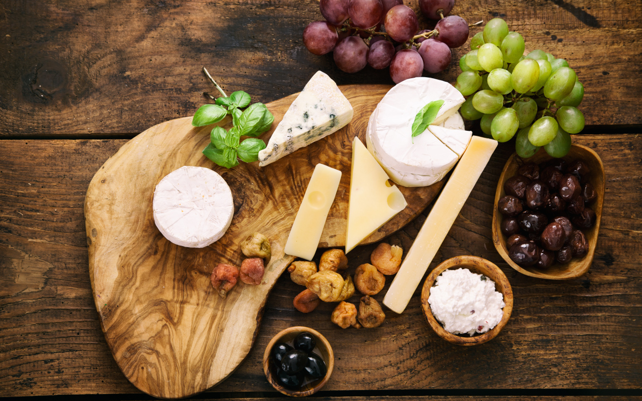Кусочки сыра с виноградом и оливками на столе