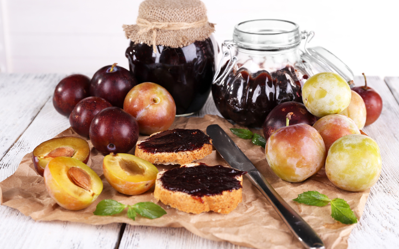 Свежие сливы и сливовый джем на столе 