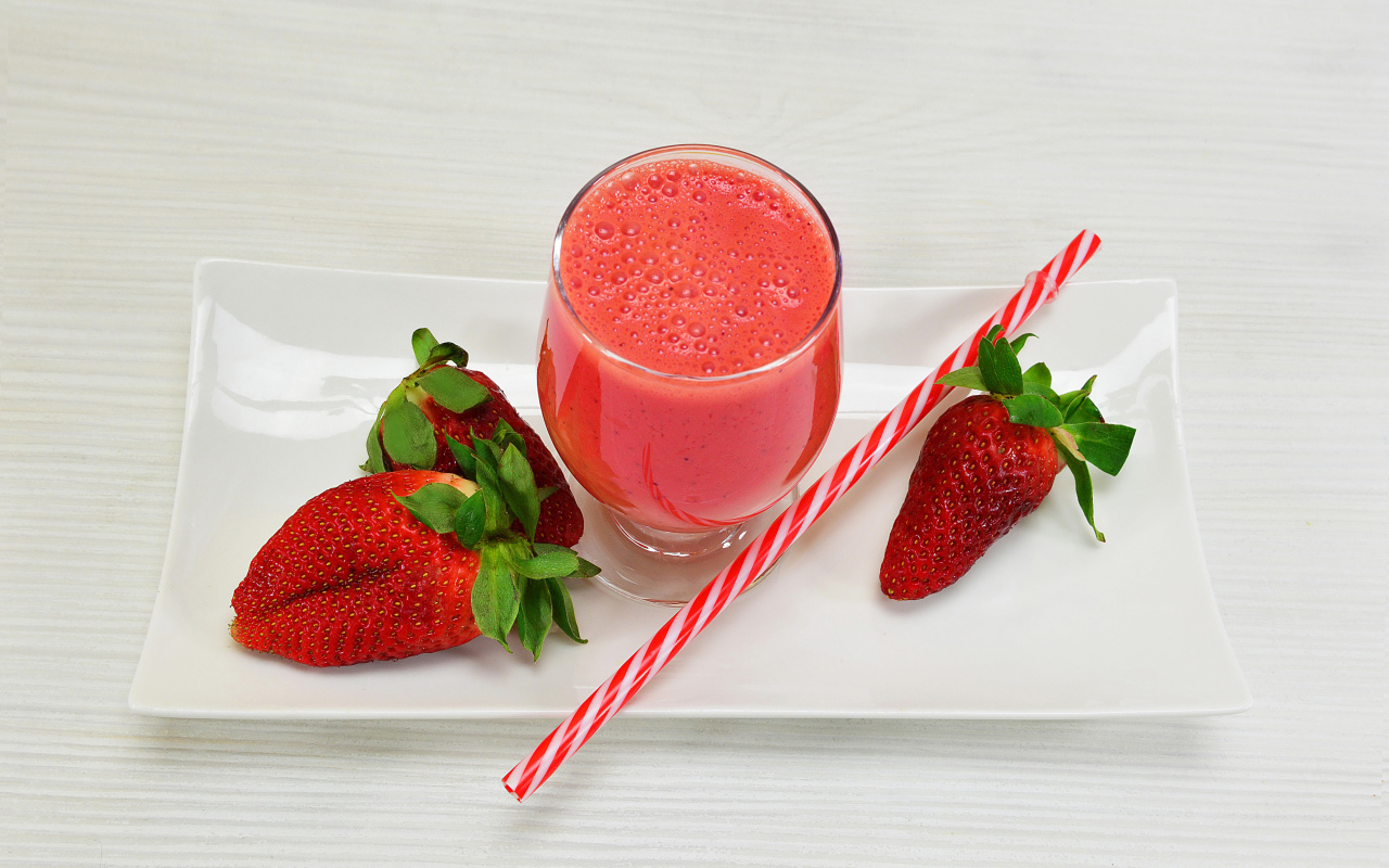 Бокал клубничного коктейля со свежей клубникой и трубочкой