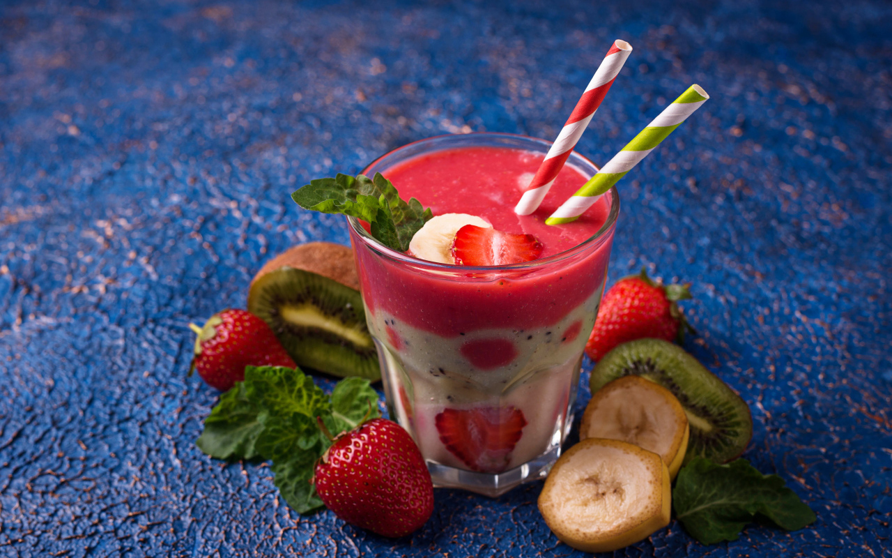 Фруктовый коктейль с клубникой, бананом и киви в стакане с трубочками
