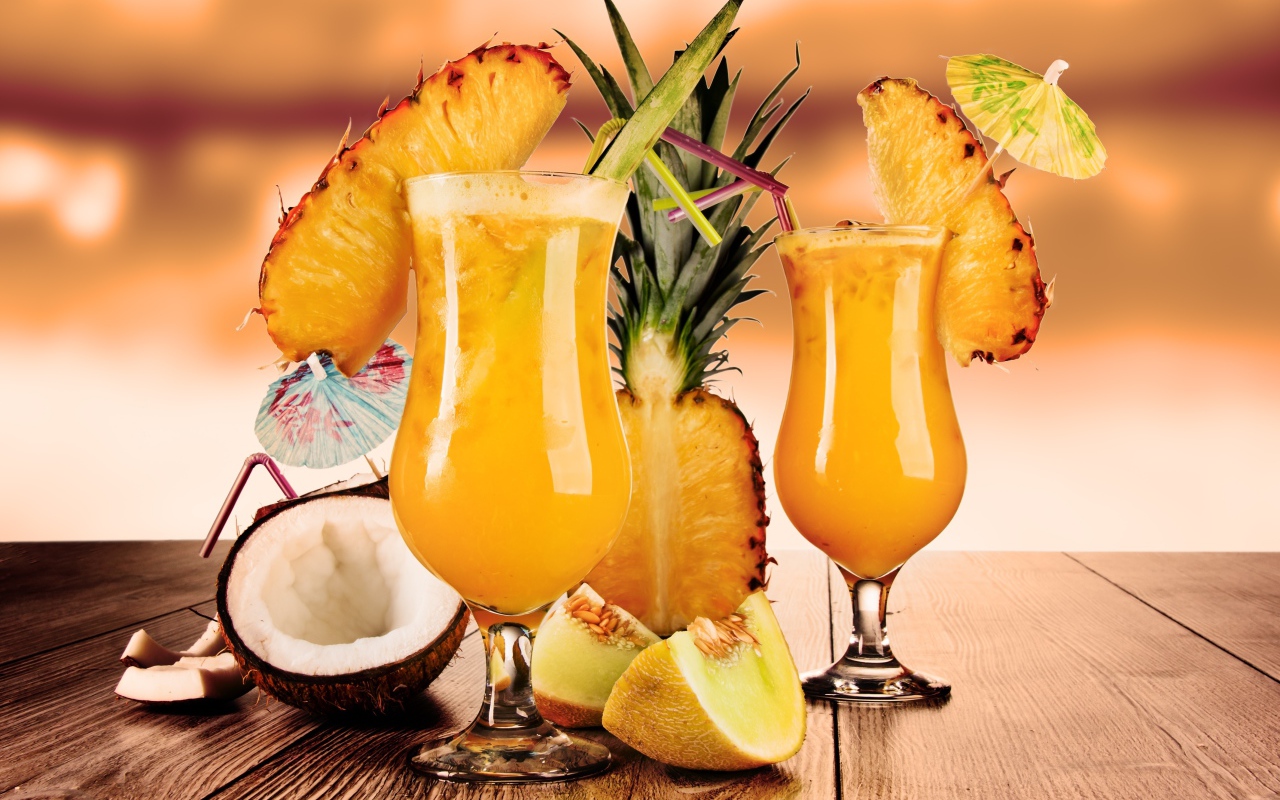 Тропические коктейли на столе со свежими ананасом, кокосом и кусочками дыни