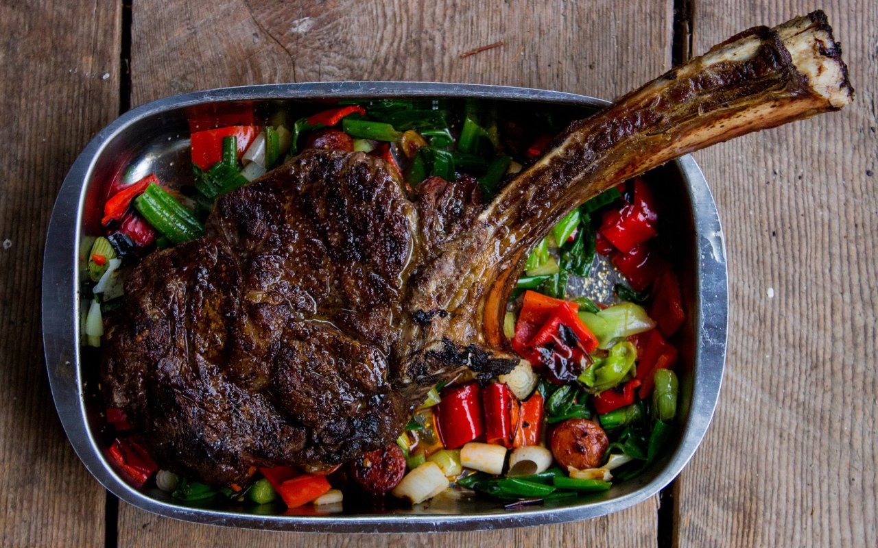 Кусок жареного мяса на ребрышке с овощами