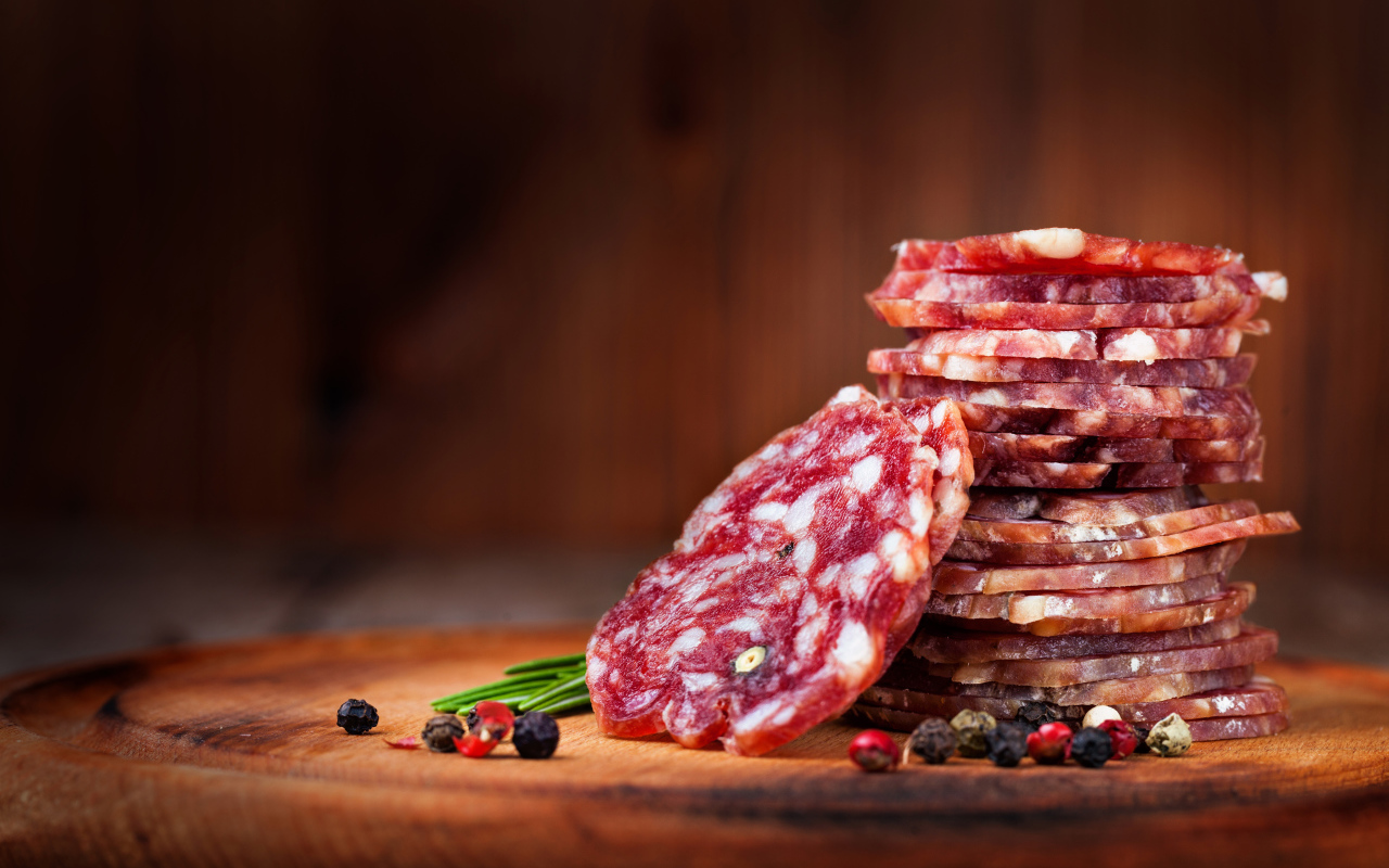 Нарезанная сухая колбаса на столе со специями