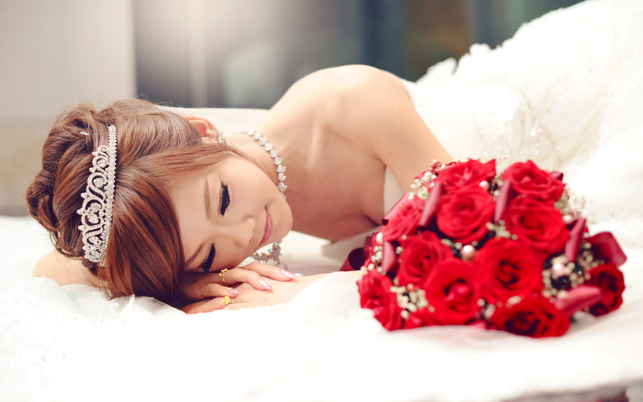 Красивая девушка азиатка в свадебном платье с букетом красных роз