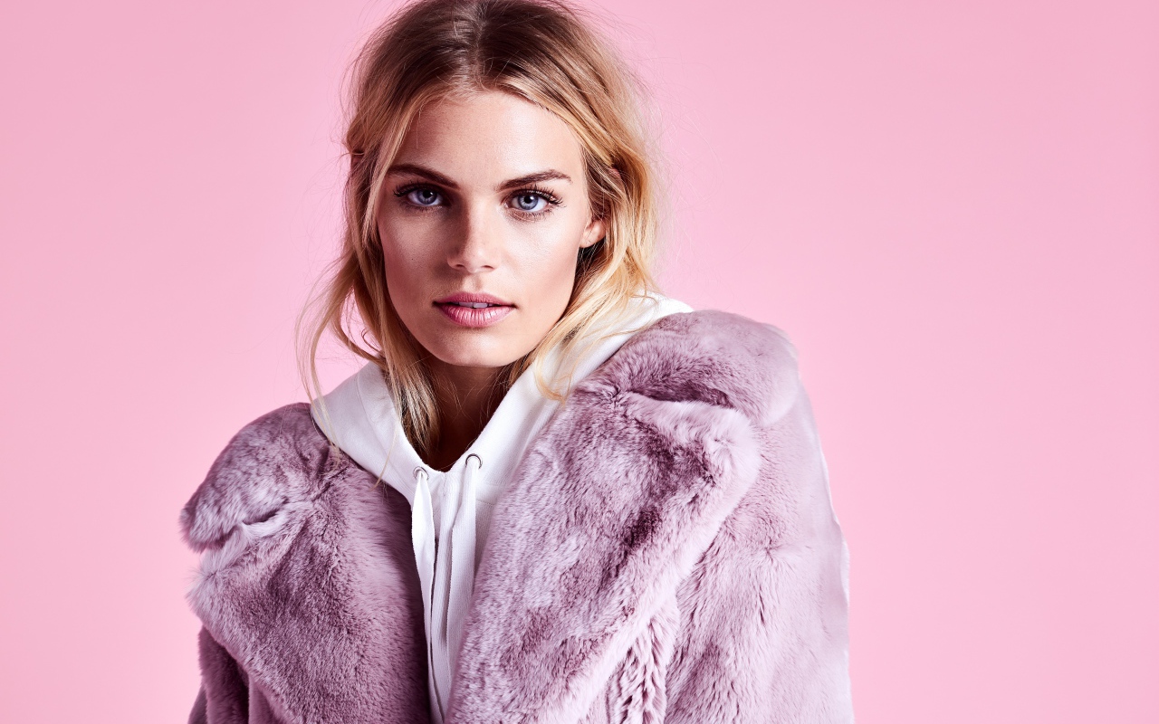 Красивая голубоглазая девушка в шубе на розовом фоне