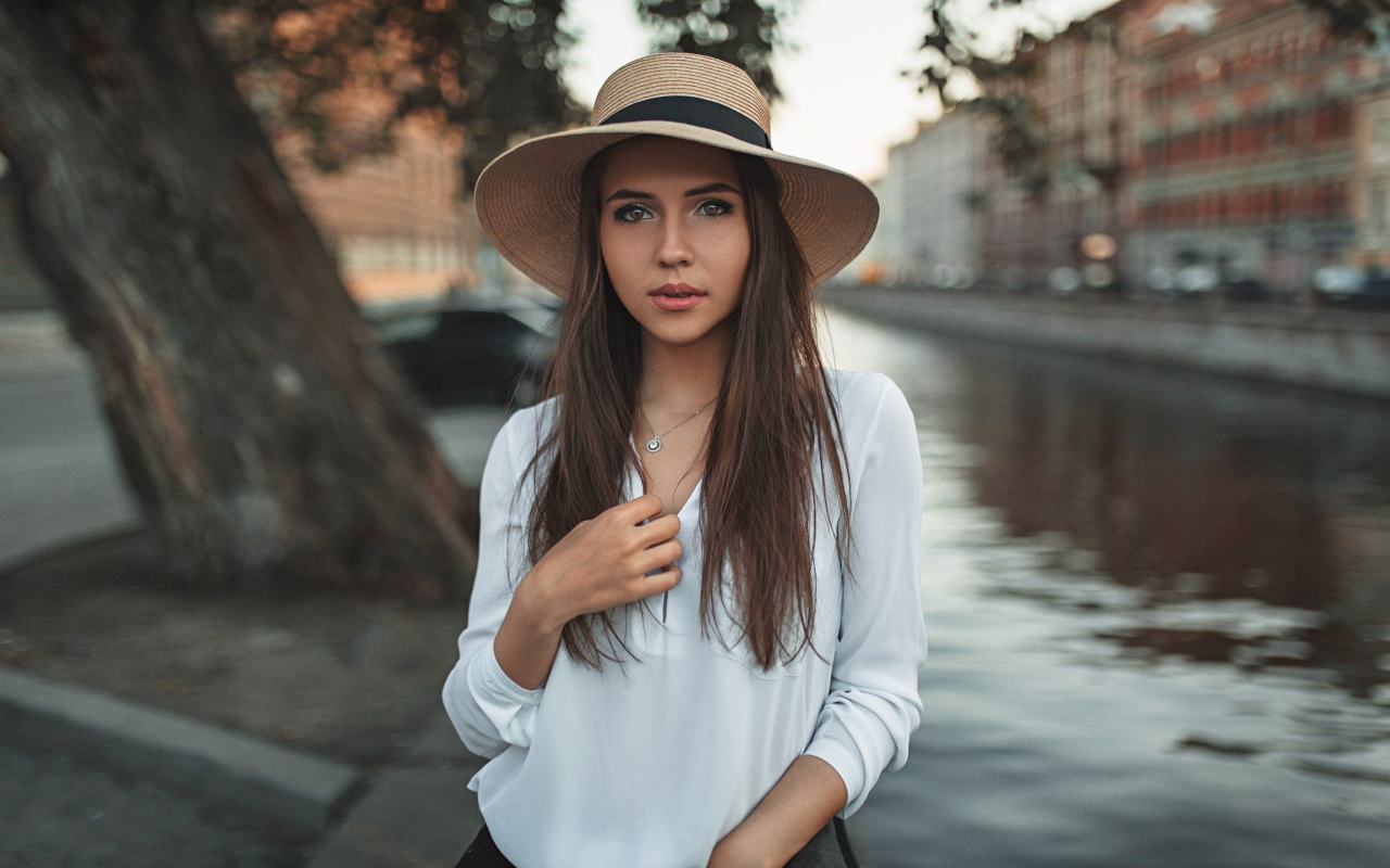 Красивая девушка брюнетка в шляпе у воды