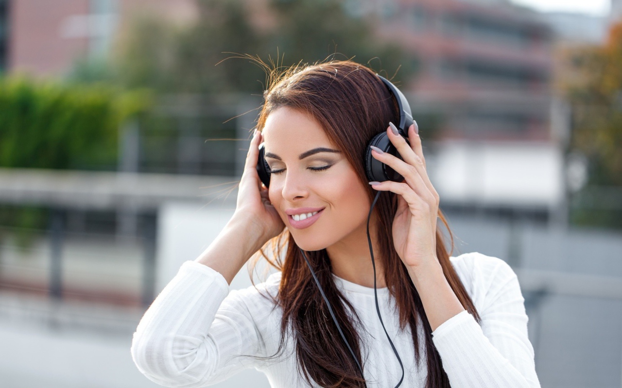 Красивая девушка брюнетка слушает музыку в наушниках 
